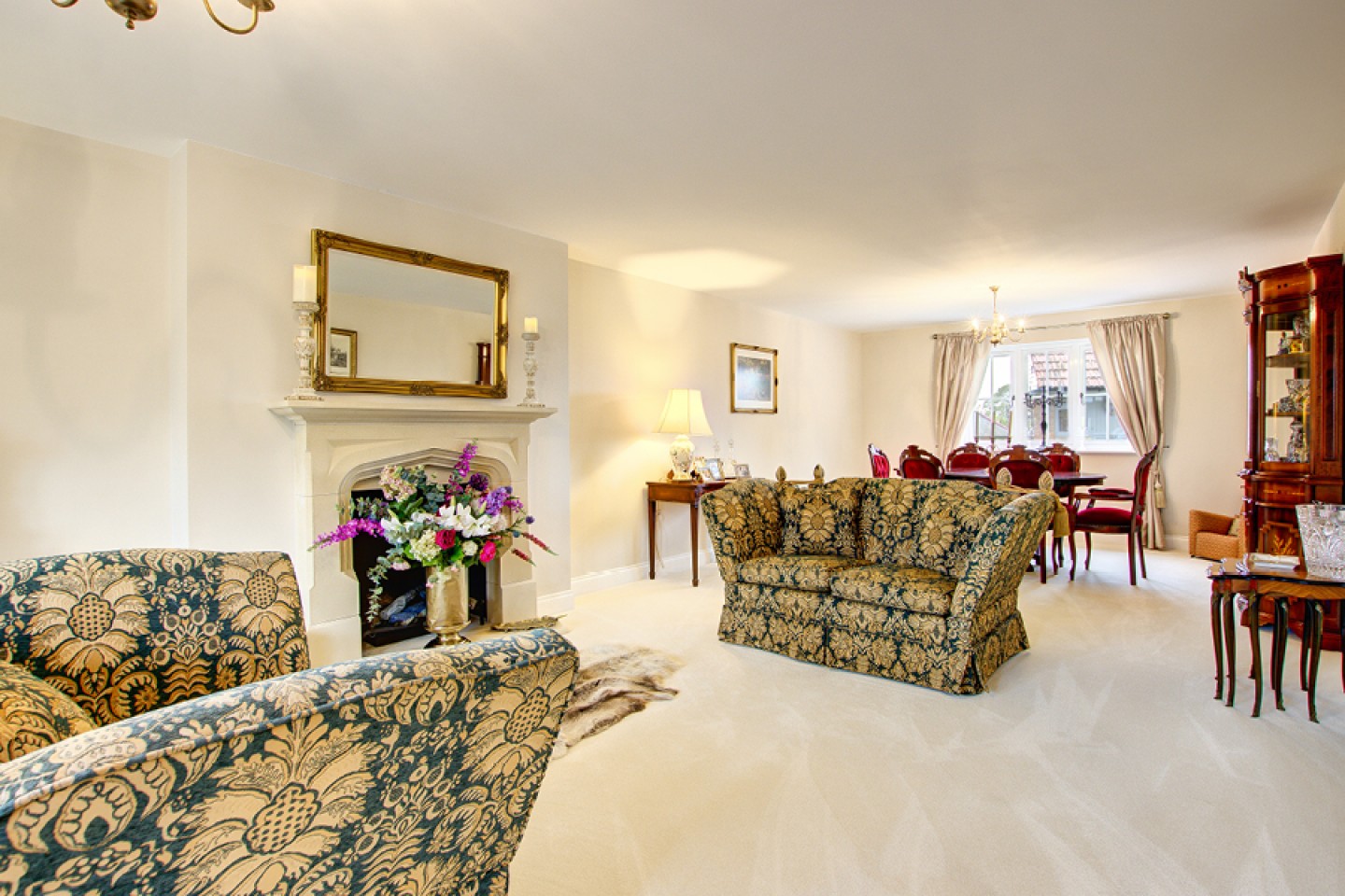 Traditional living area with heavy print chairs, fireplace and dining set to the rear